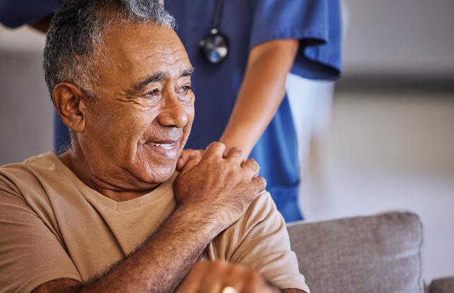 A patient smiling with healthcare professional hand on his shoulder